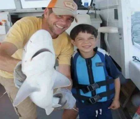 Captain and child with a small shark caught on a fishing charter